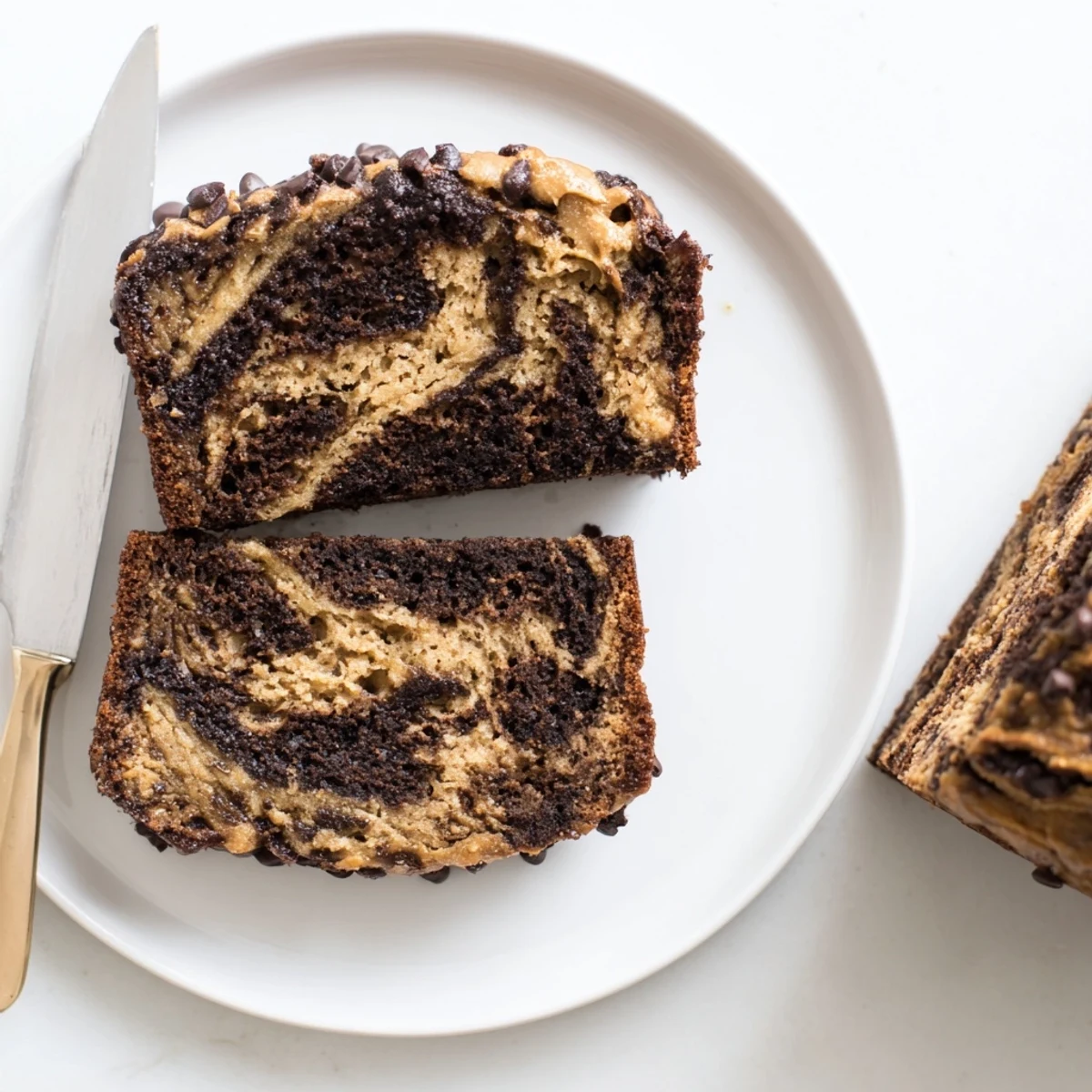 Freshly baked chocolate peanut butter banana bread loaf with golden crust, dolloped with creamy peanut butter and garnished with chocolate chips
