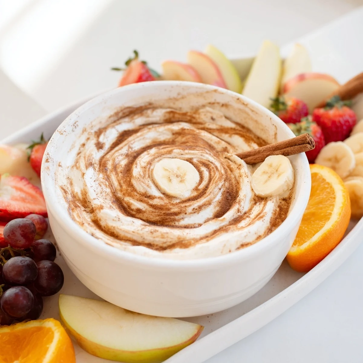 Creamy healthy Greek yogurt cinnamon roll dip served with fresh sliced apples and strawberries