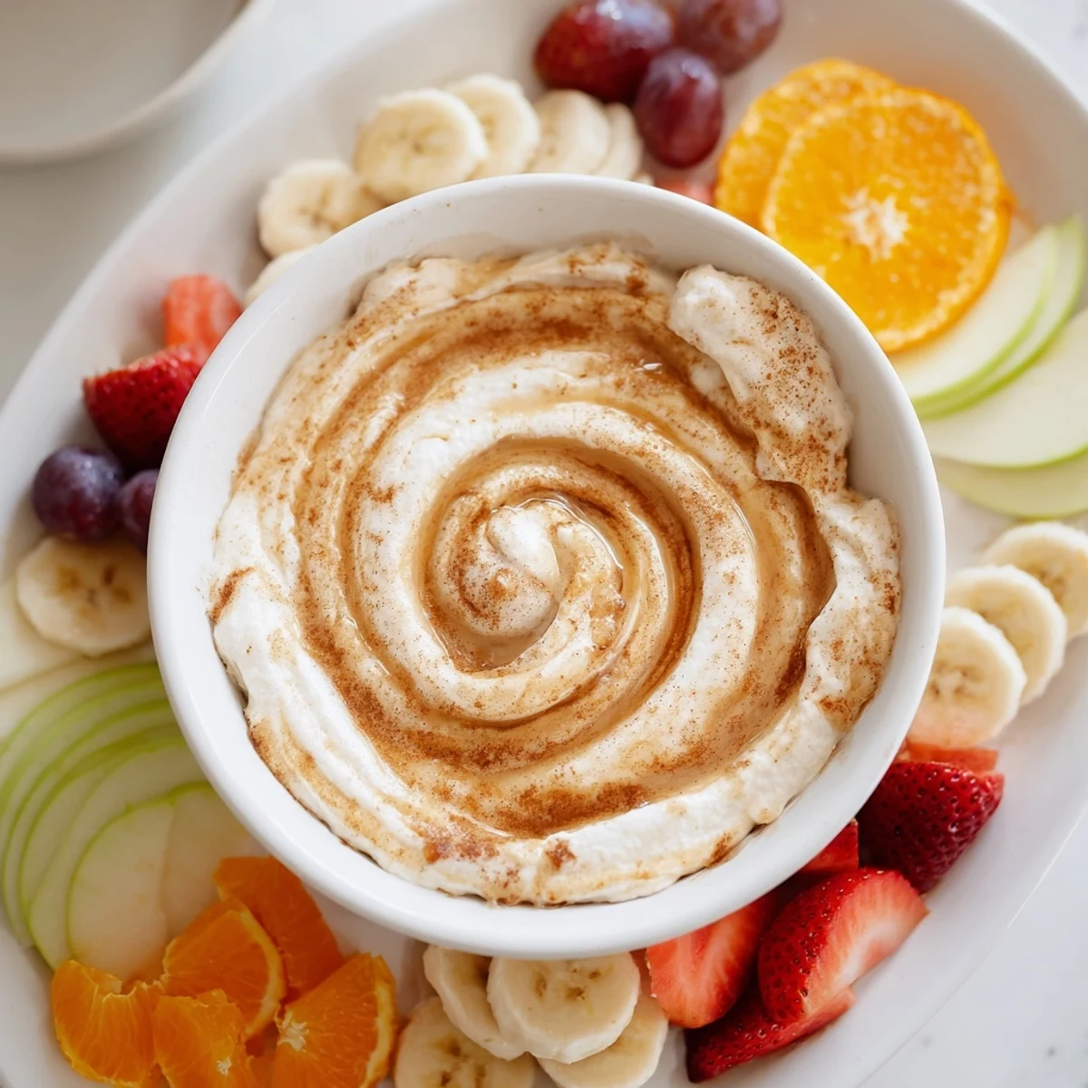 Wholesome Greek yogurt cinnamon roll dip bowl surrounded by colorful apple pear and strawberry dippers