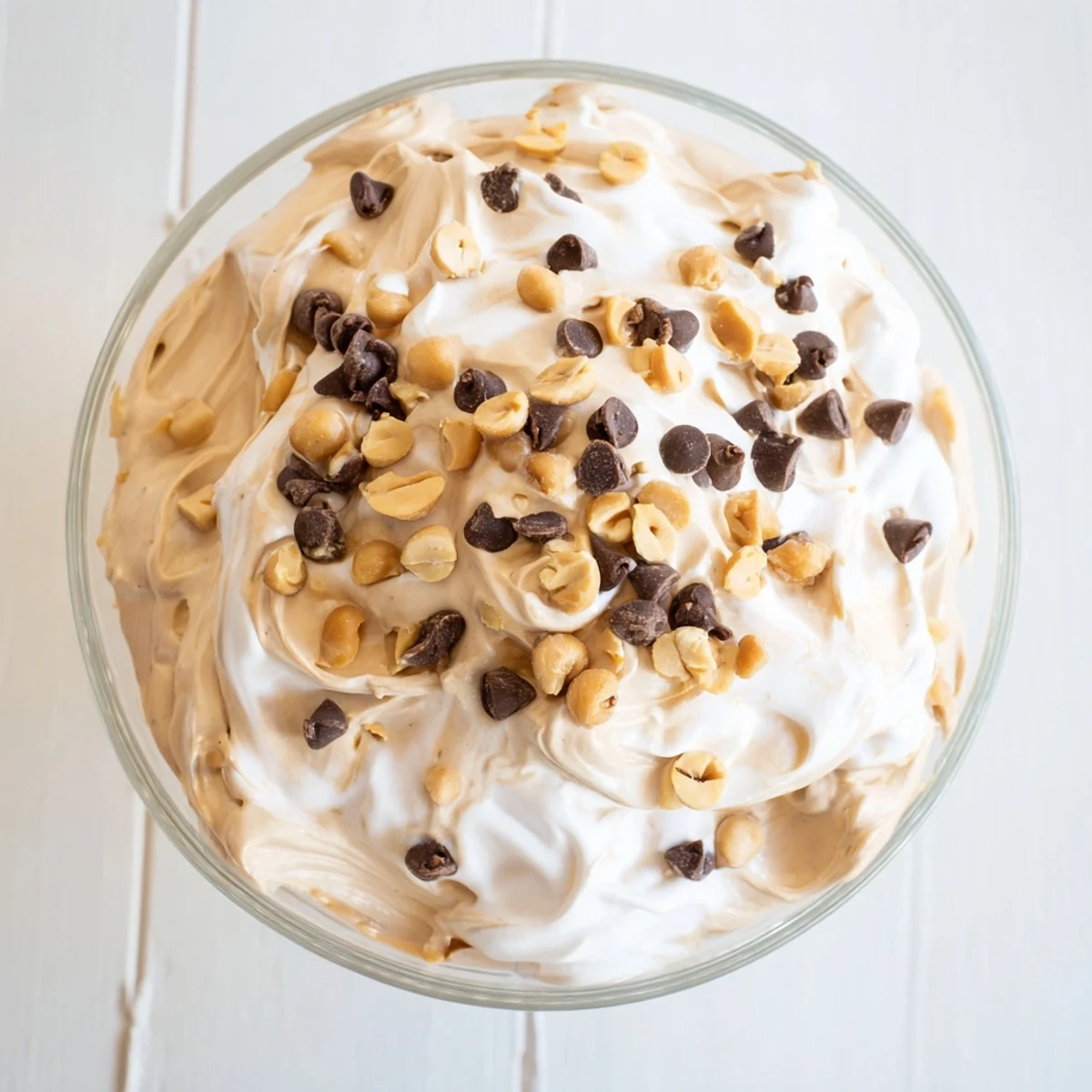 Creamy peanut butter and Cool Whip mousse topped with chocolate chips and chopped roasted peanuts in glass serving dishes