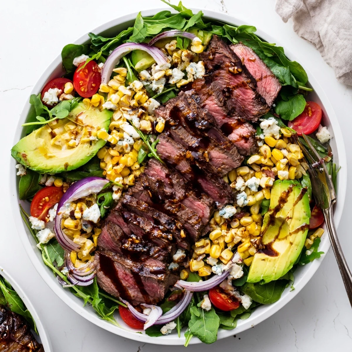 Juicy sliced balsamic steak gorgonzola salad topped with charred grilled corn