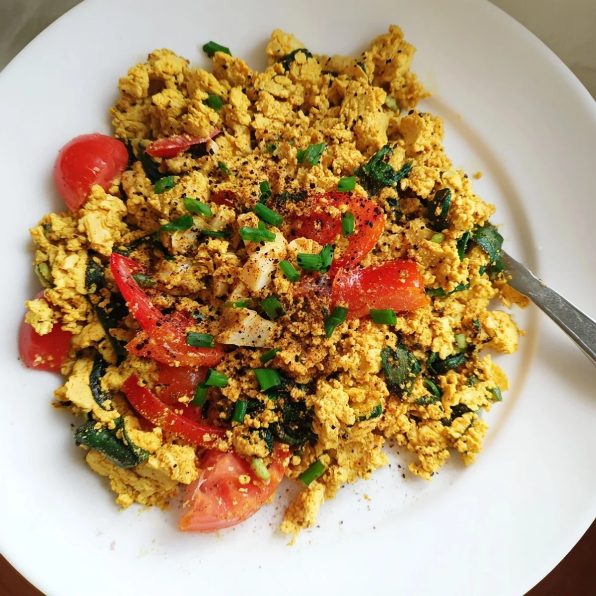Tofu Scramble steaming in skillet with turmeric-golden curds and wilted spinach