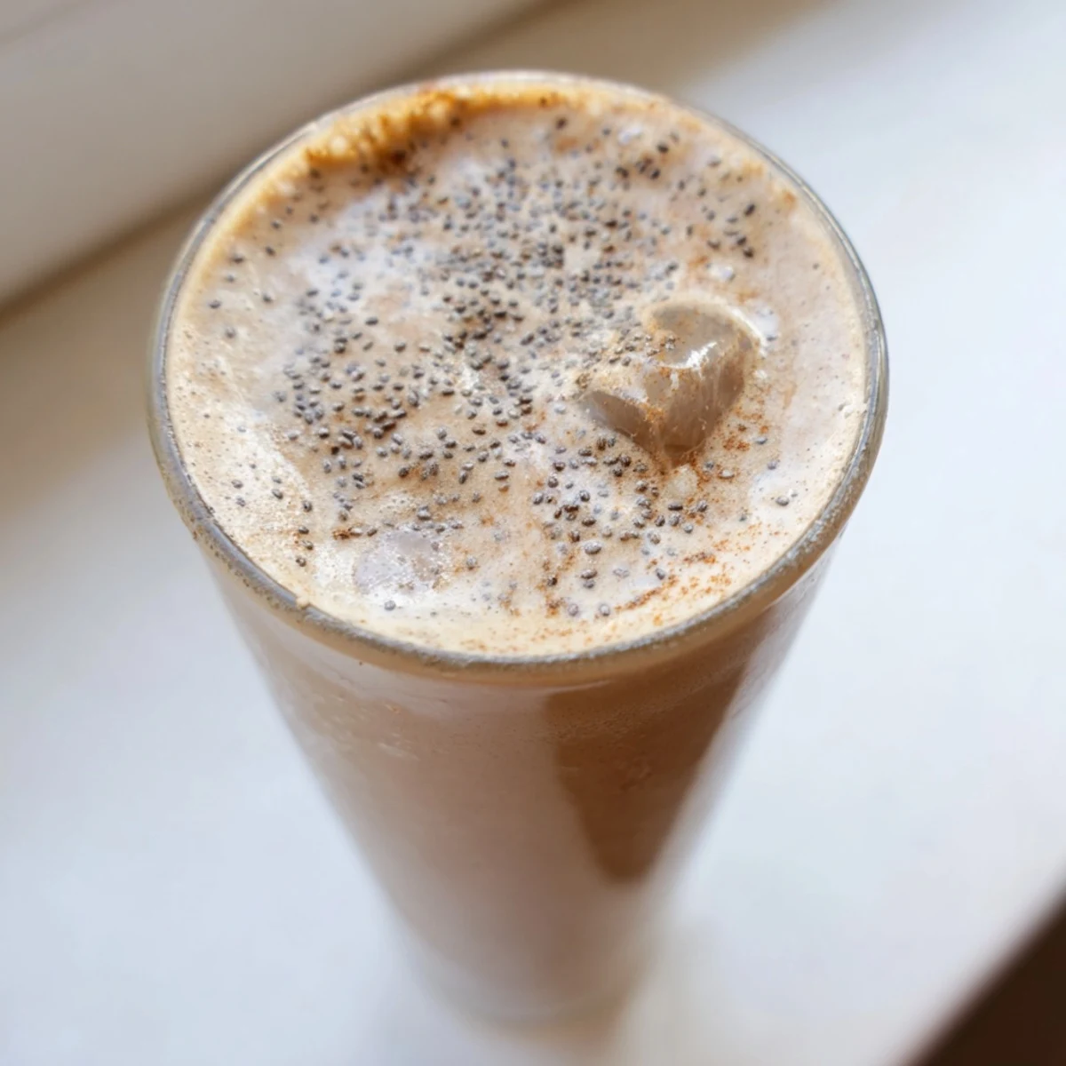 Thick frothy banana protein coffee smoothie poured over ice for morning energy