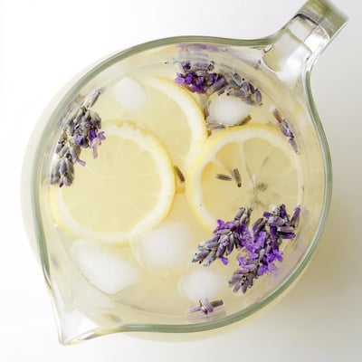 Refreshing lavender lemonade served over ice in mason jars with purple lavender flowers floating