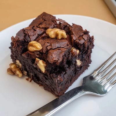 Warm ultimate brownies served with vanilla ice cream on a rustic white plate
